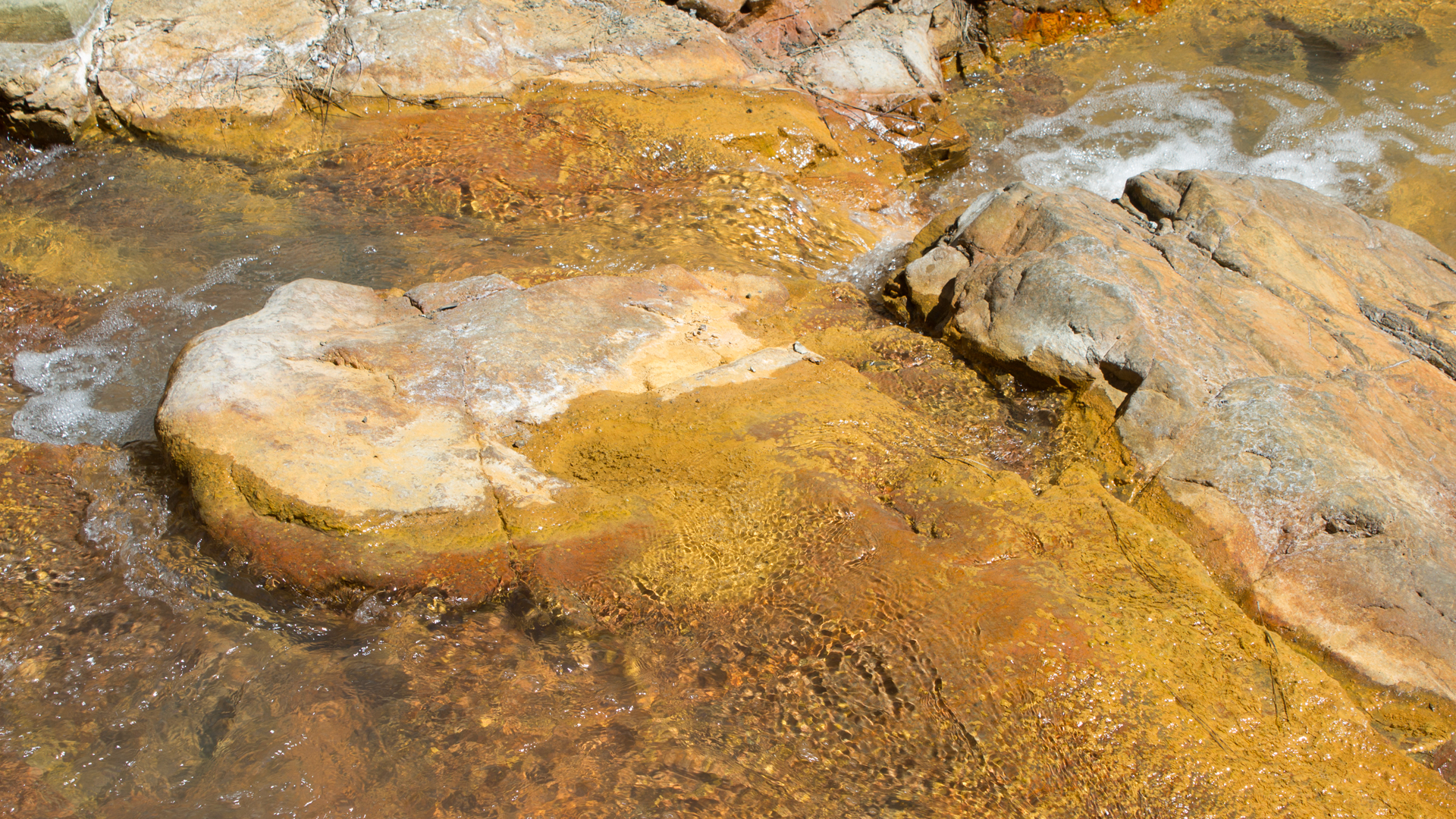 das Flussbett des Río Rivanceras leuchtet in Rot, Gelb und Ocker