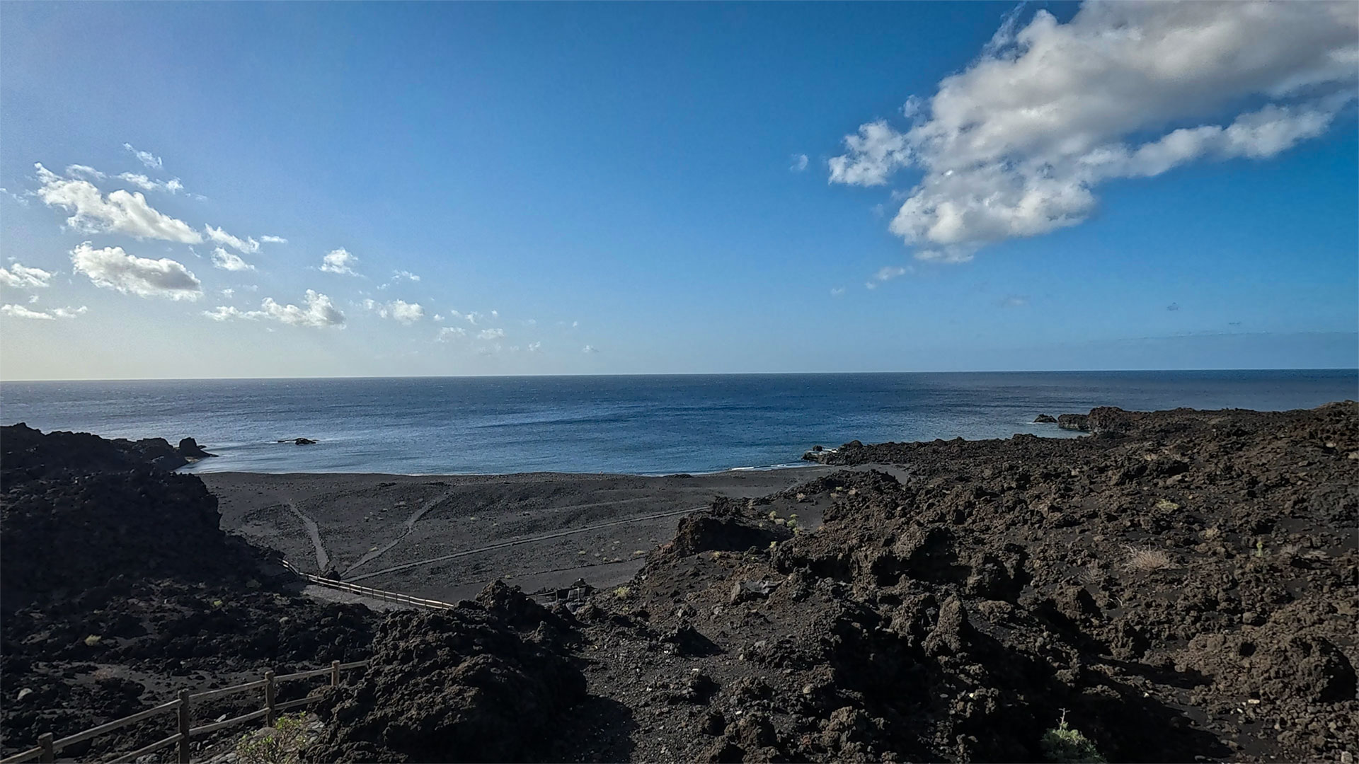 Schwarzer Vulkansand, umrahmt von den kargen Lavafeldern des Teneguía – die Playa Echentive an der Südspitze La Palmas